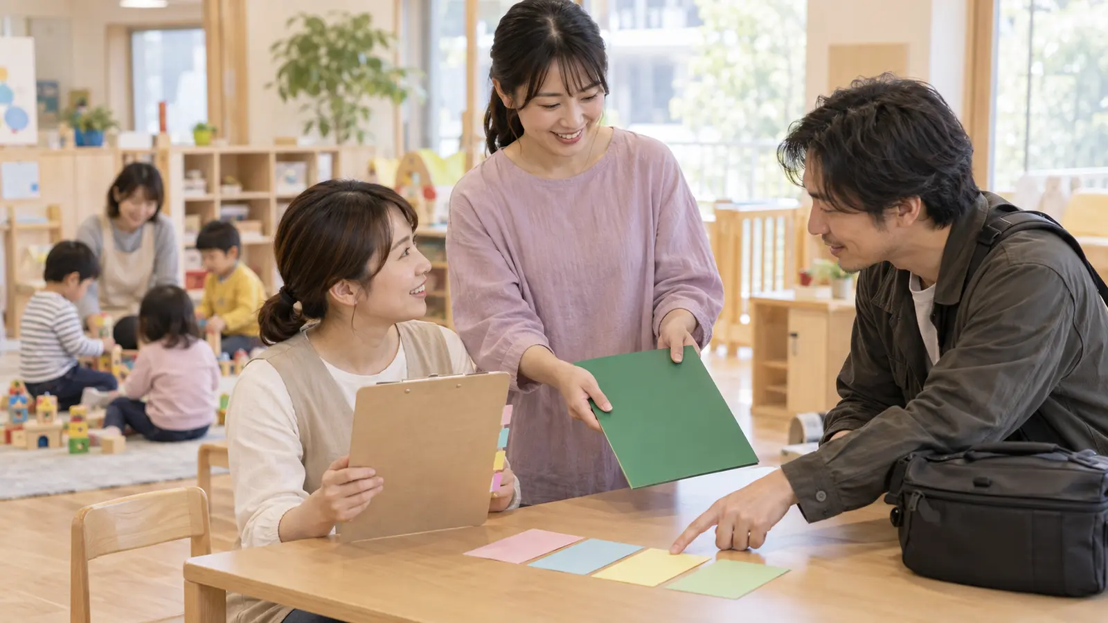 保育室の一角で先生が撮影会社との連絡内容を別の先生へ引き継ぐ場面